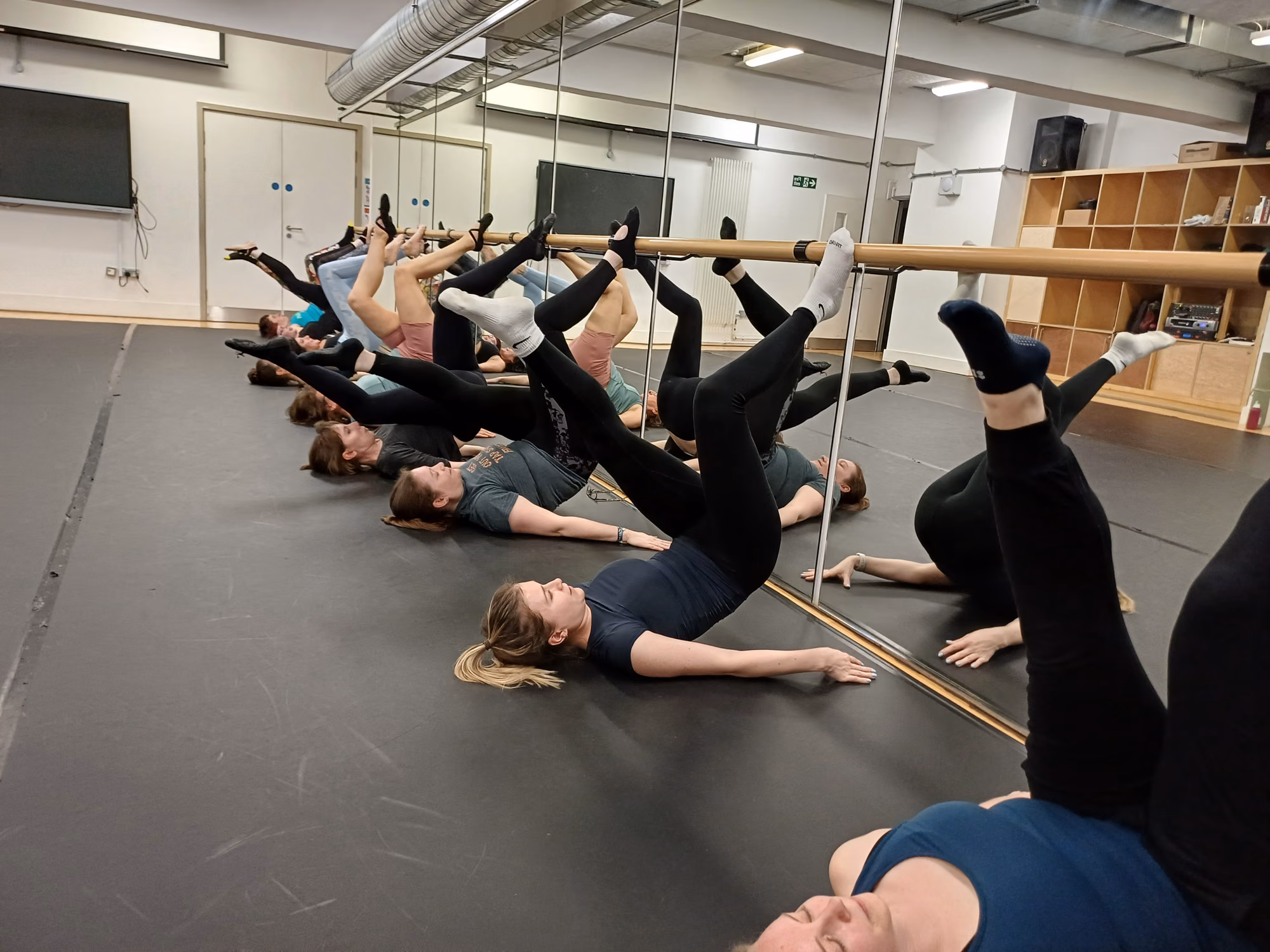 Stretch and Mobility class, students lying on mats lengthening through the body with one leg raised